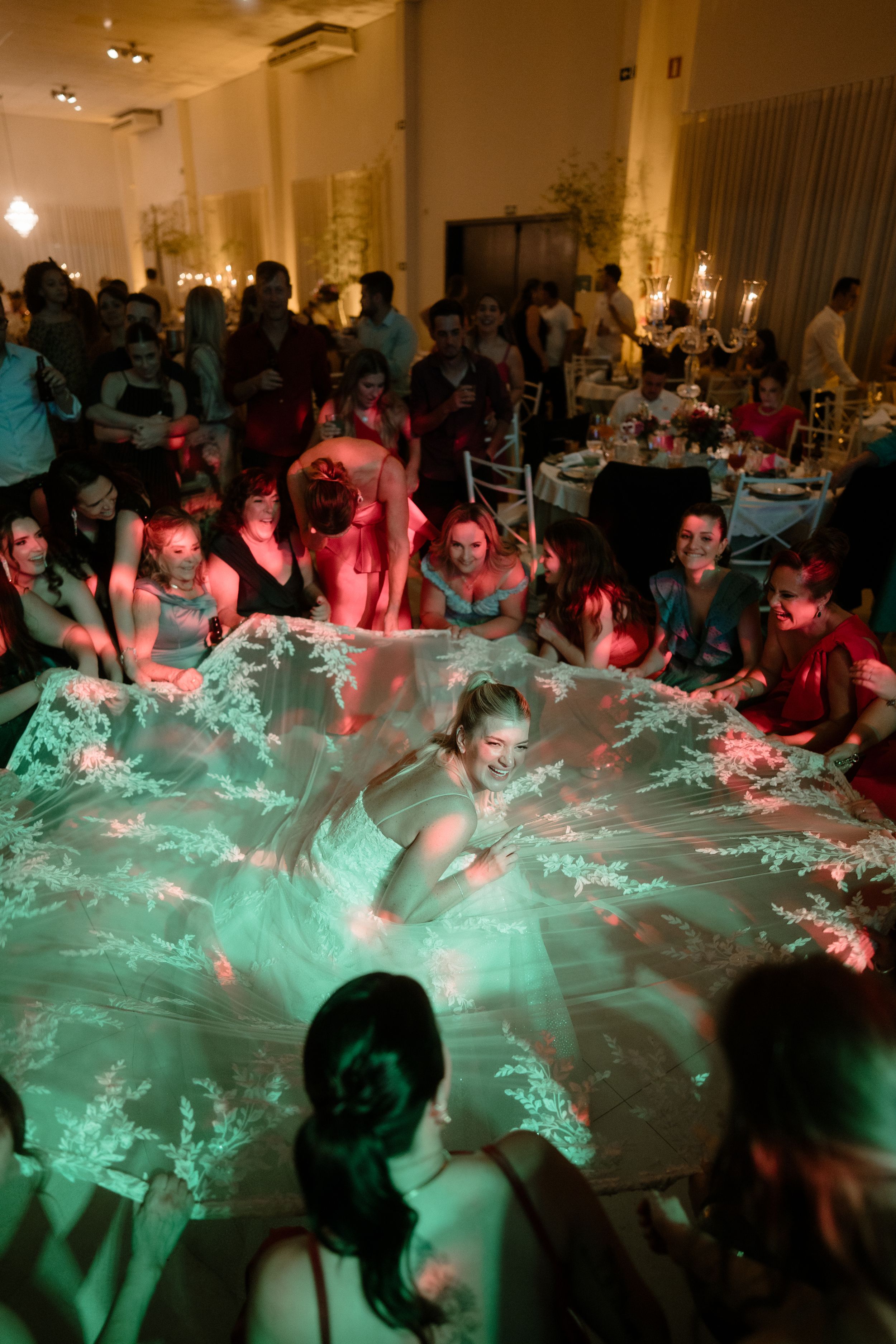 Wedding reception guests dance under dramatic turquoise lighting creating a dynamic party atmosphere.