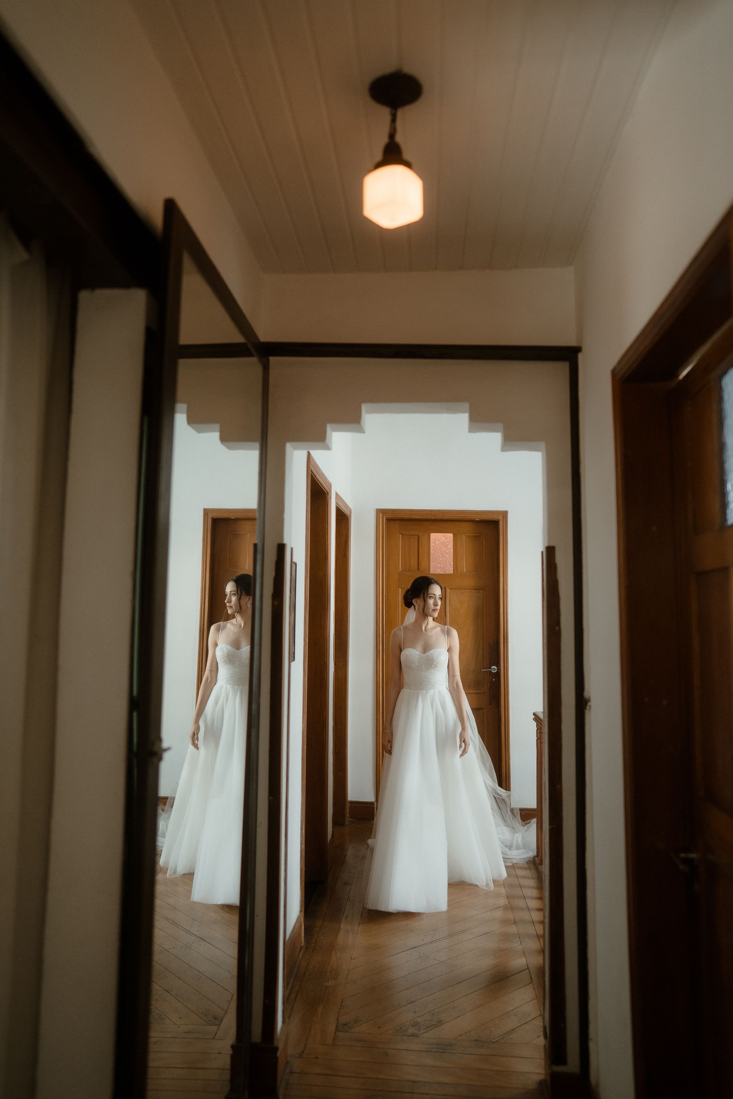 A series of haunting hallway photographs showing white wedding dresses suspended in dimly lit corridors.