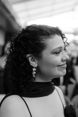 Black and white portrait showing a profile view of someone with curly dark hair wearing a black turtleneck and dangling earrings.