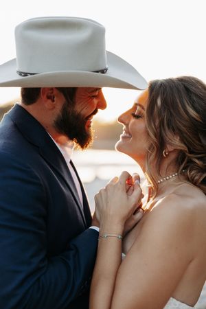 Intimate close-up wedding portraits captured during golden hour with a cowboy hat silhouette.