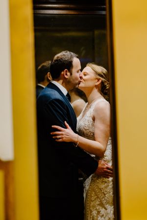 Romantic wedding couple sharing a kiss in warm golden lighting.