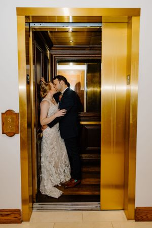 Couple shares romantic dance moves in a golden-lit elevator during their wedding celebration.