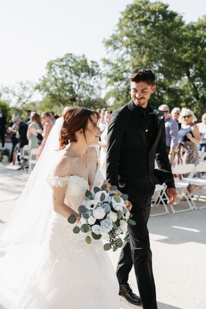 Bride and groom share an intimate moment during their outdoor wedding ceremony on a sunny day.