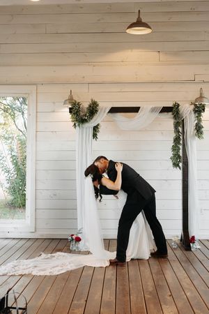 A romantic wedding moment captured at a rustic white chapel with greenery garlands and wooden floors.