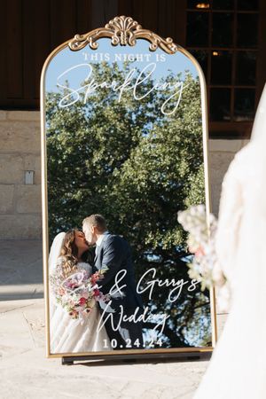 A series of vintage-style mirrors display wedding signage text against a rustic stone wall backdrop.