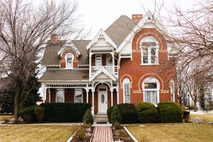 A row of classic red brick houses with white trim and architectural details line a residential street in winter.