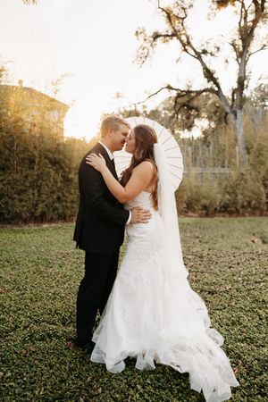 A romantic outdoor wedding photoshoot with a couple embracing in a natural setting during golden hour.