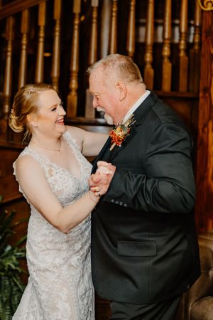 Bride and older gentleman sharing a joyful dance moment at wedding reception.