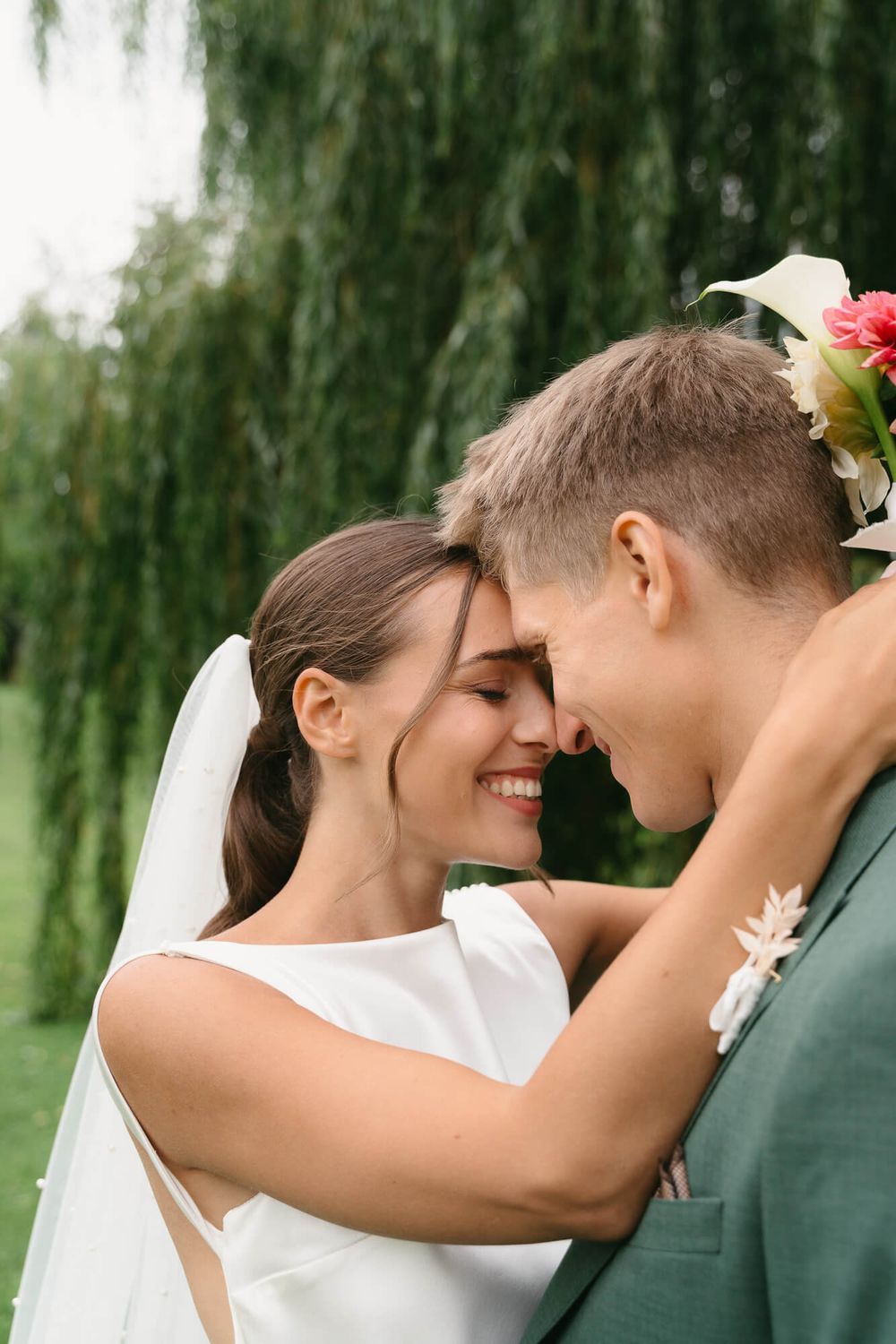 A romantic wedding couple shares intimate moments in a series of photos with willow trees in the background.