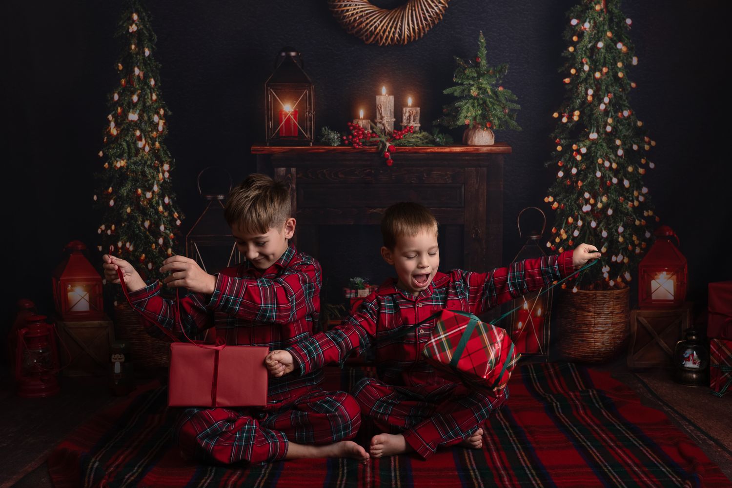 Children in matching buffalo plaid outfits sit on a dark floor near a decorated Christmas tree with presents.