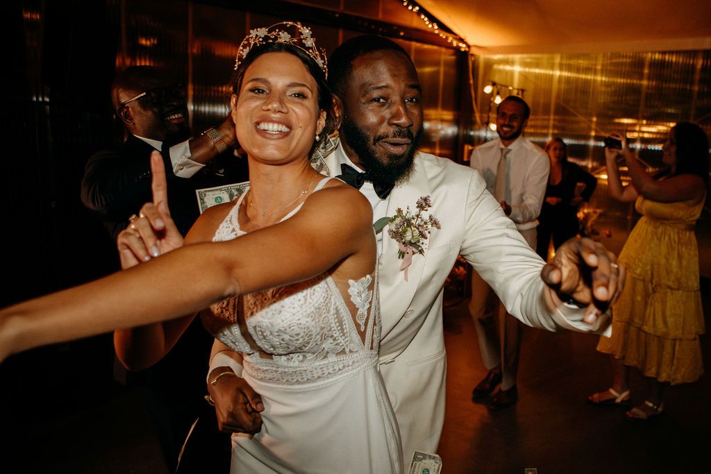 Bride and groom dancing joyfully together at lively wedding reception surrounded by guests.