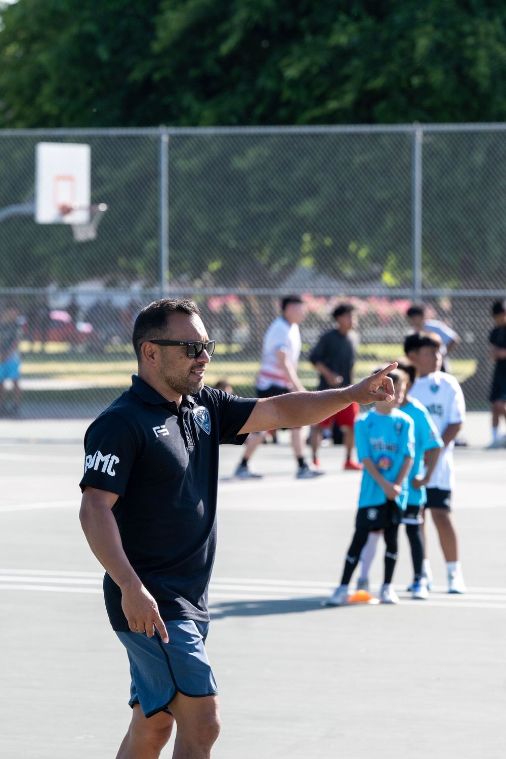Coaches directing youth sports activities on an outdoor court.