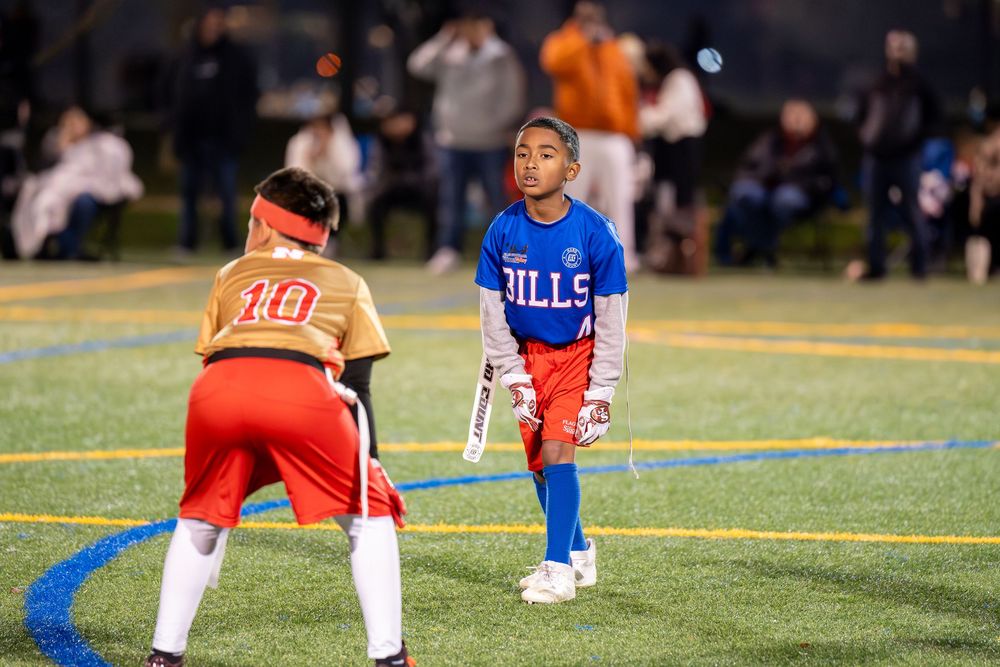 Two young athletes face off on illuminated sports field at night during game.