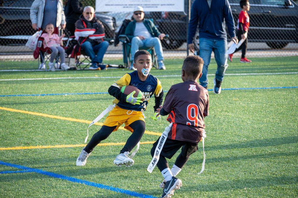 Youth football players competing for the ball during a match on artificial turf.