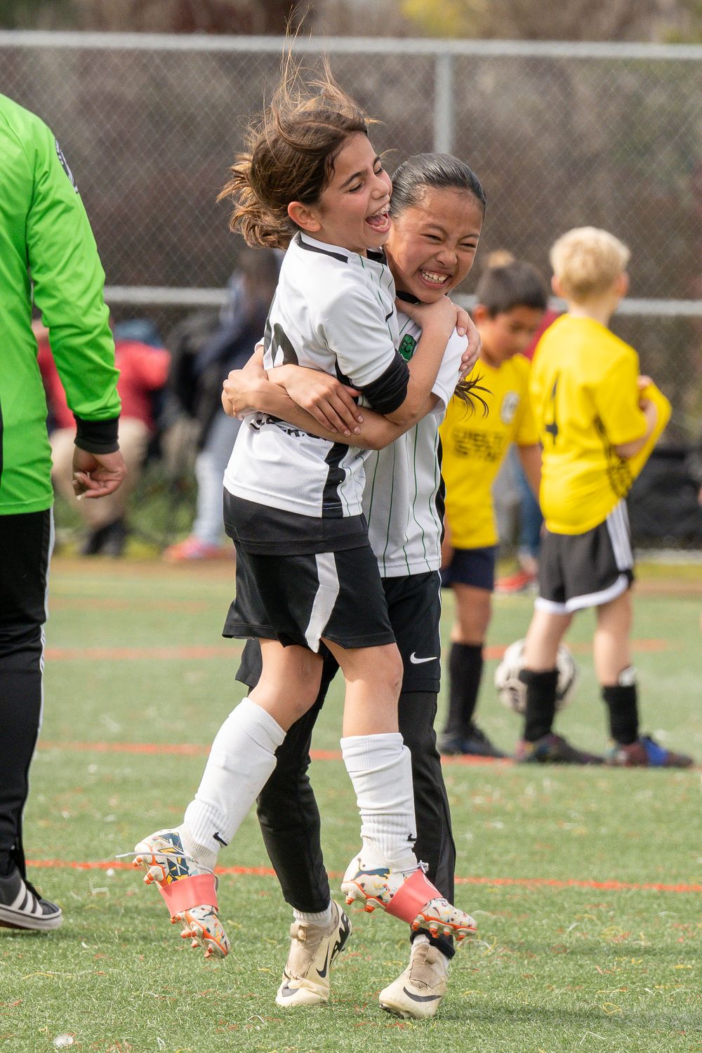 Two soccer players share joyful celebration hug on field during game.