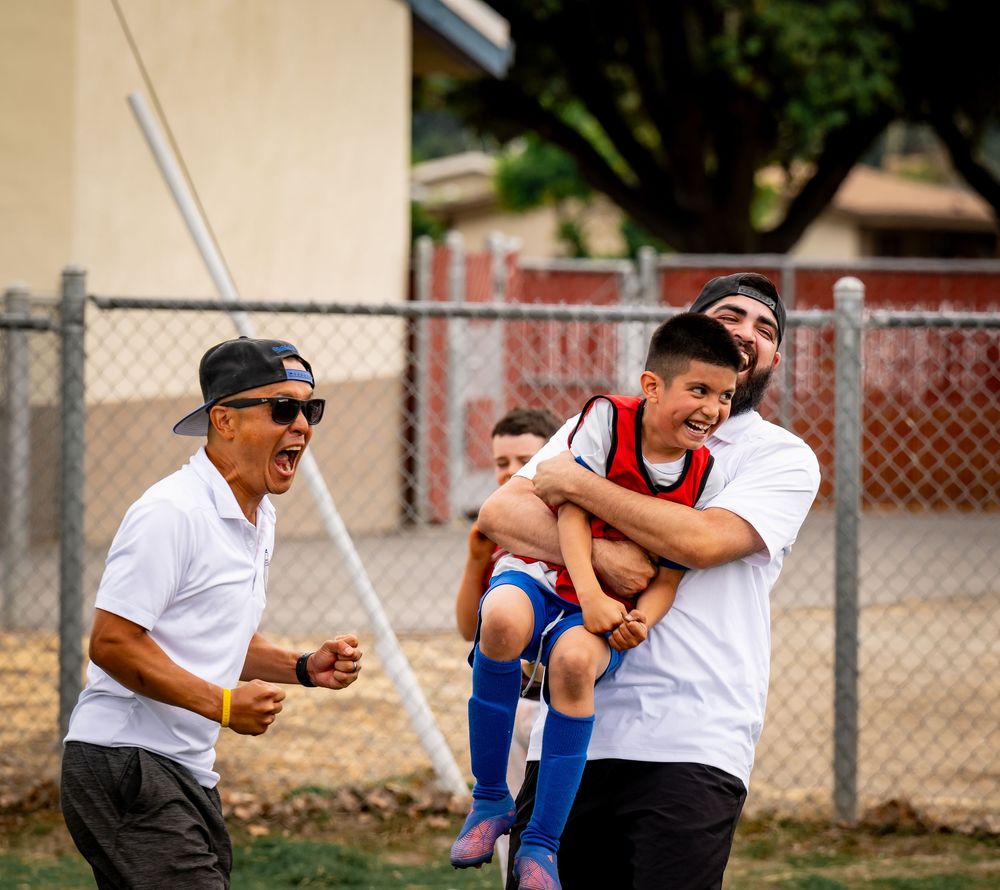 Soccer players celebrating and hugging on a field after a game.