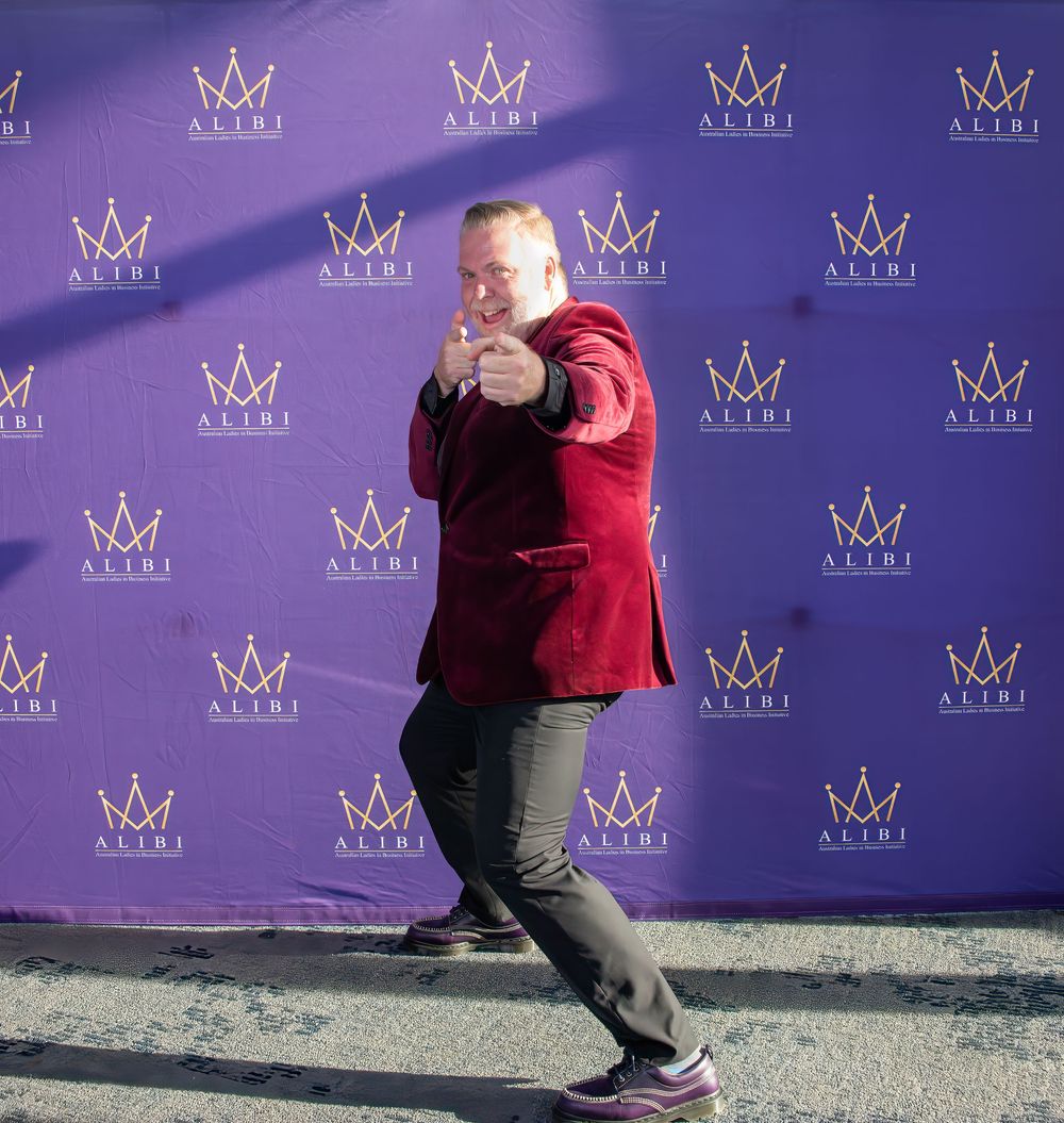 Purple step-and-repeat backdrop with crown logos at formal event.