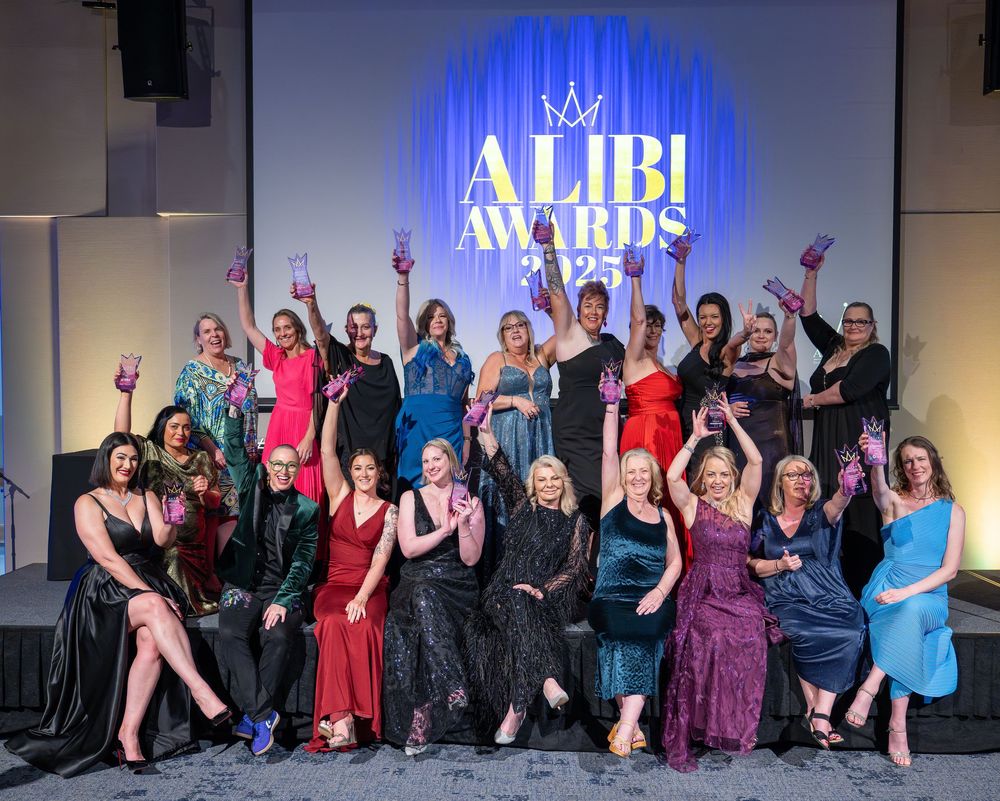 Group photo of attendees posing together at an awards ceremony with blue backdrop and crown logo.