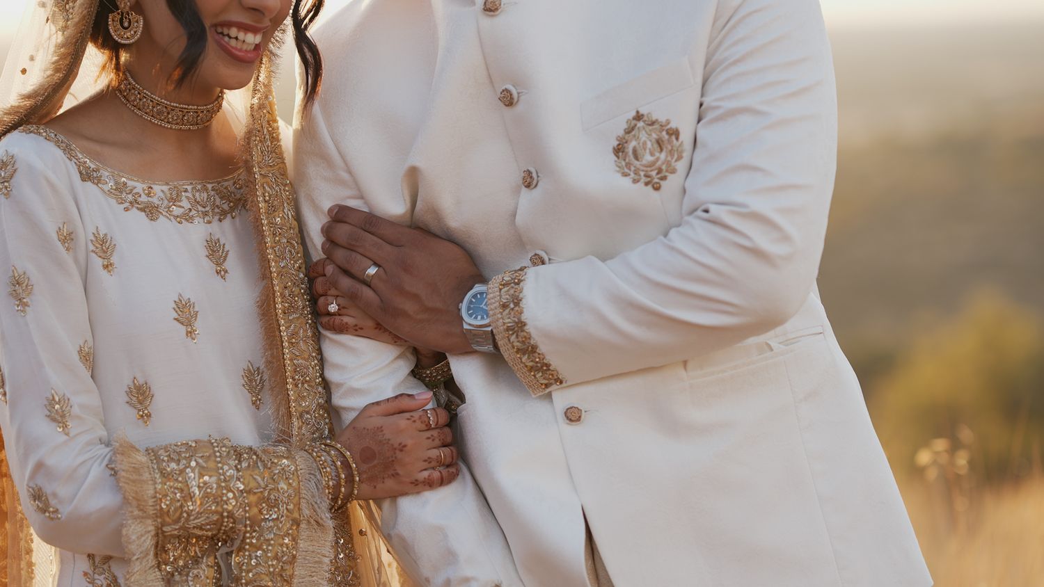 Couple in matching white and gold outfits sharing a tender moment during their wedding.