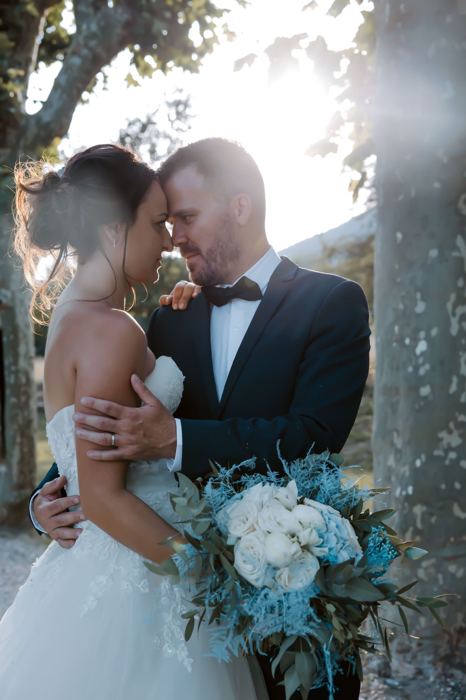 Romantic sunset portrait of newlyweds with blue and white bouquet in natural setting. Domaine la Plume photographe mariage