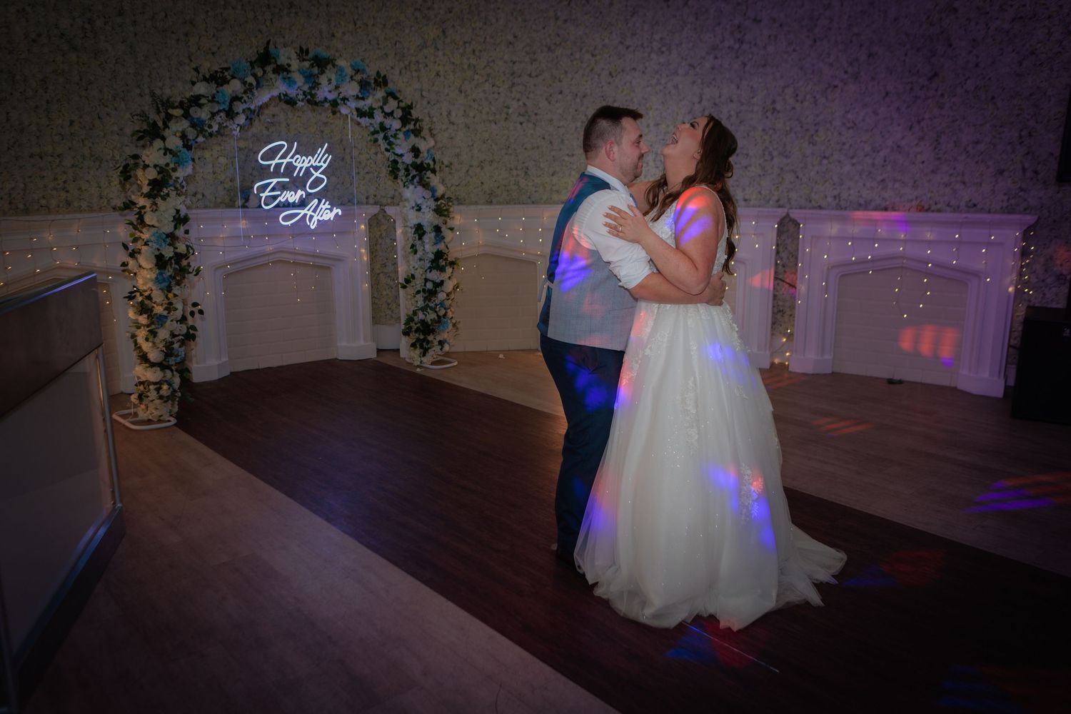 A romantic first dance between newlyweds at their wedding reception under soft purple lighting.