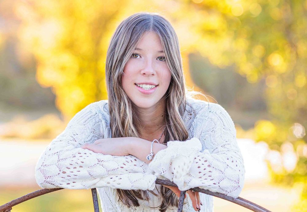 Smiling teen girl in white lace top leaning on rustic branch. Gilmanton NH.
