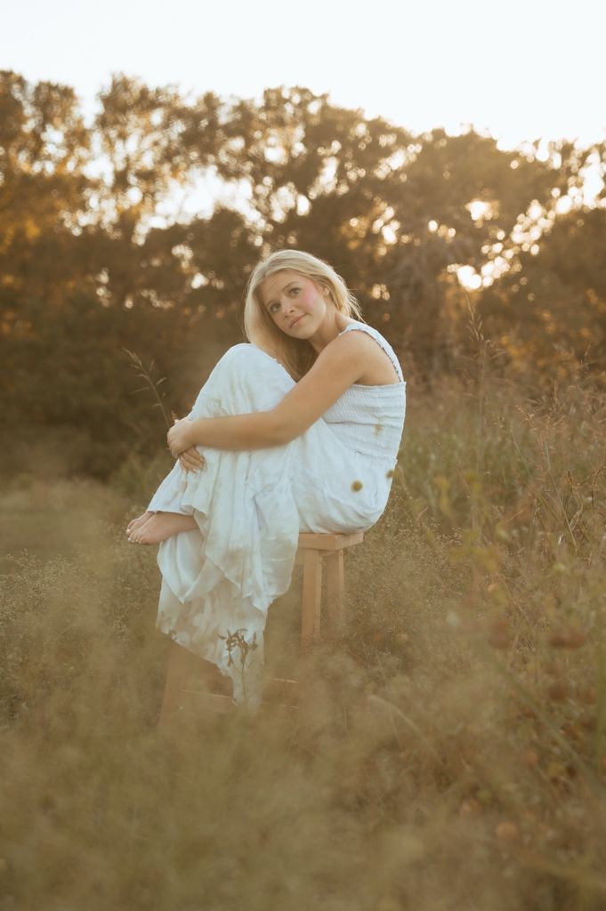 Ethereal outdoor portrait session with flowing white fabric and glowing sunset light through tall grass.