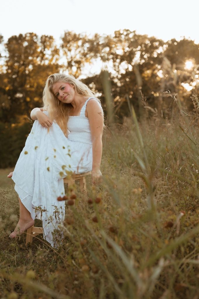 A dreamy sunset photoshoot in a golden wildflower field with soft natural lighting and flowing white dress.