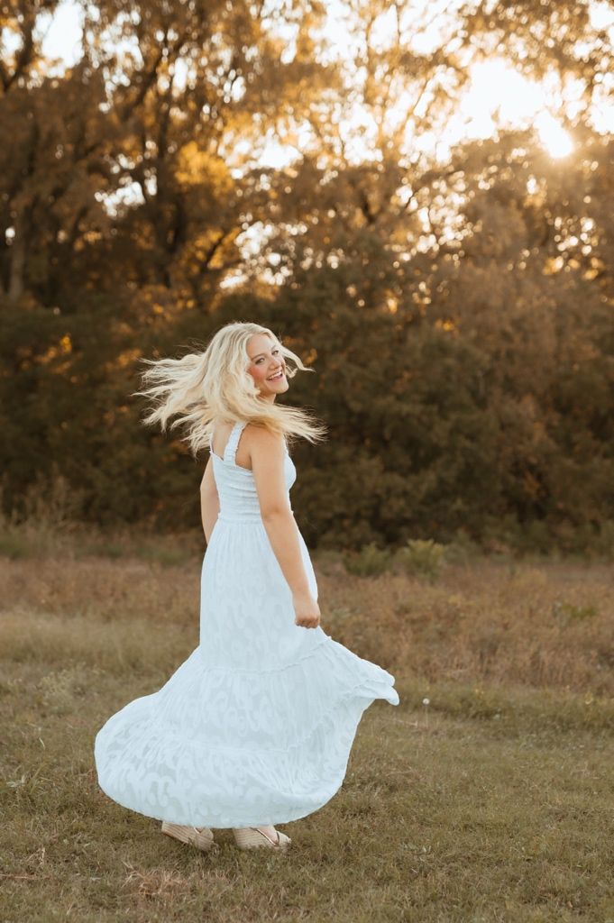 A white dress spins and flows in the warm evening light against a natural outdoor backdrop.