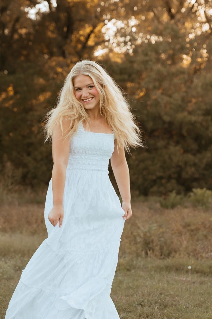 A light summer dress dances and swirls in the golden hour light with trees in the distance.