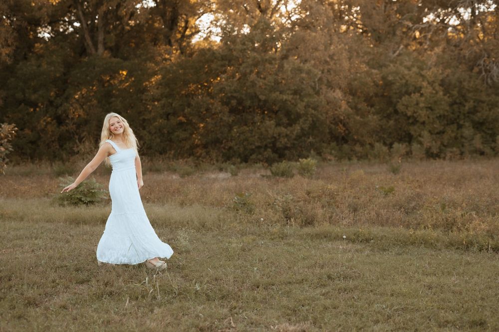 A dreamy golden hour photoshoot in a field with a white dress and warm autumn lighting.