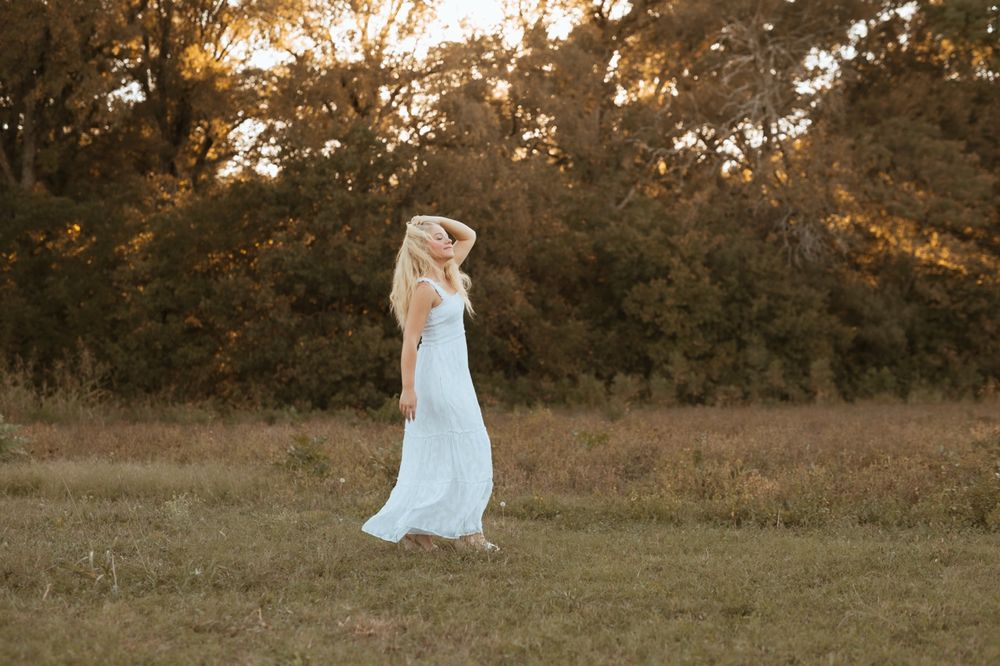 A light blue dress flows gracefully in a golden-lit meadow during sunset.