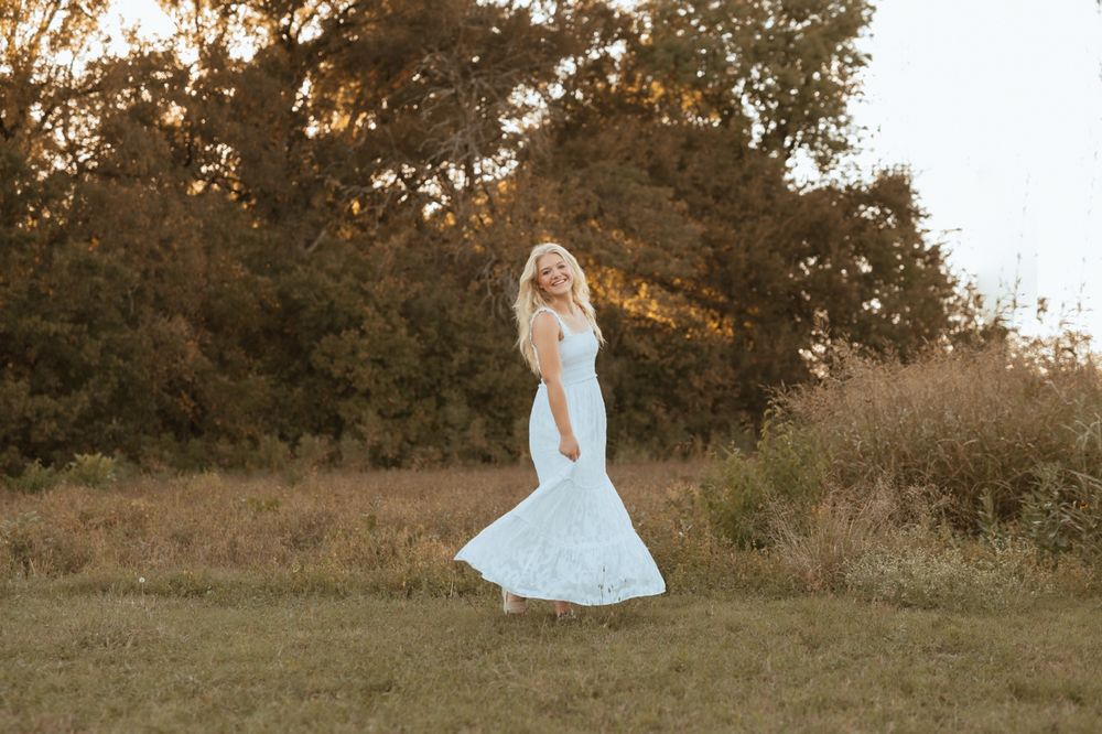 A flowy white dress twirls against a warm autumn backdrop at golden hour.