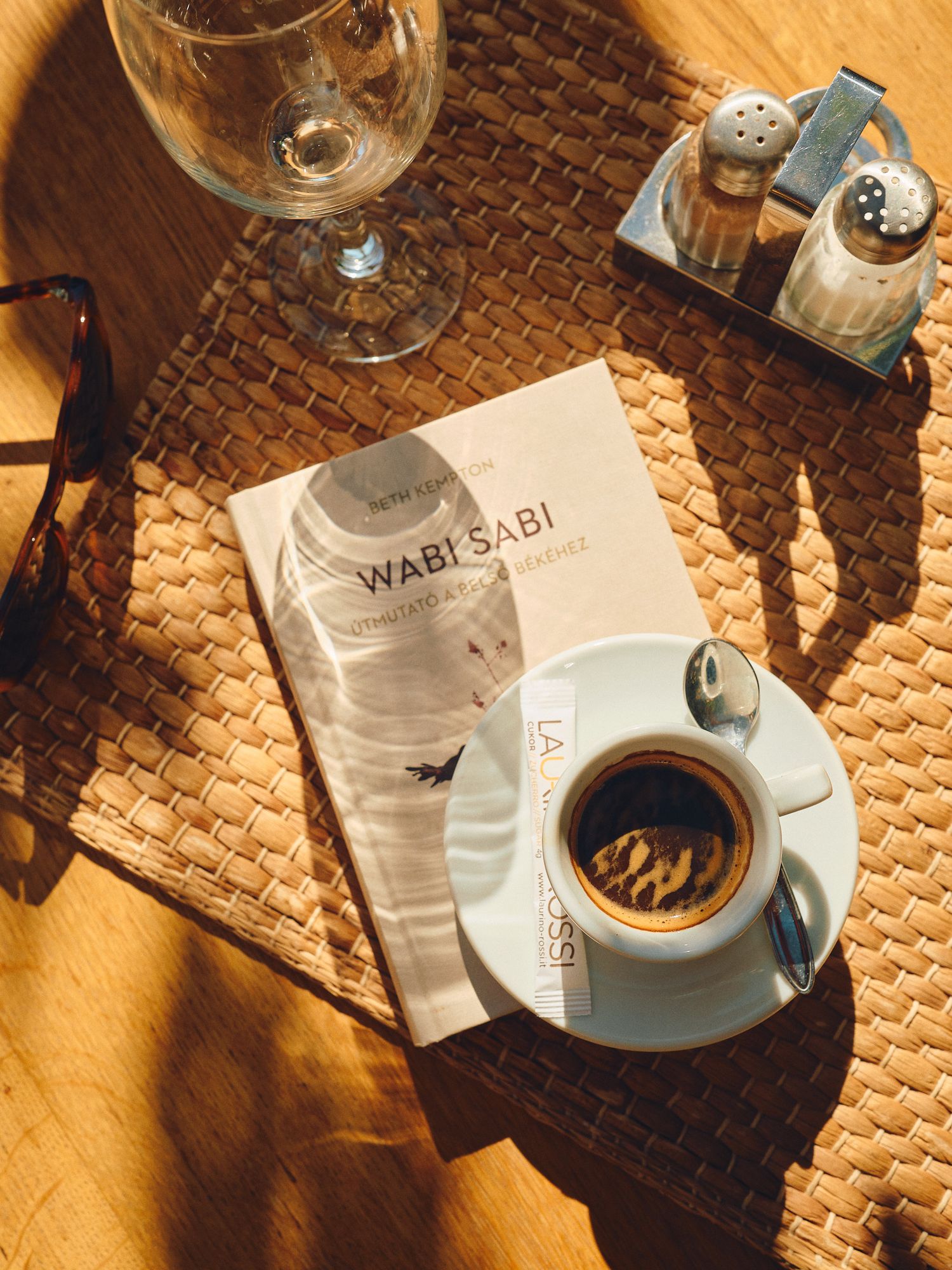 Coffee cup and menu from Wabi Sabi cafe sits on textured placemat in warm sunlight.