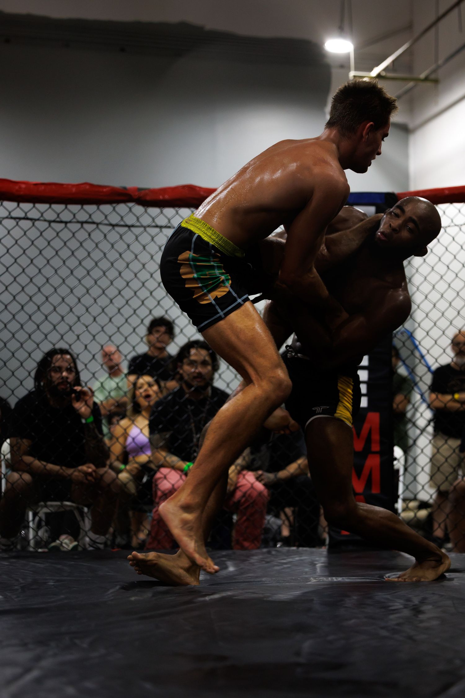 Two MMA fighters grappling on the mat during an intense match sequence.