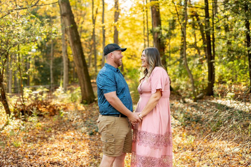 Couple holding hands and gazing at each other in a colorful autumn forest.