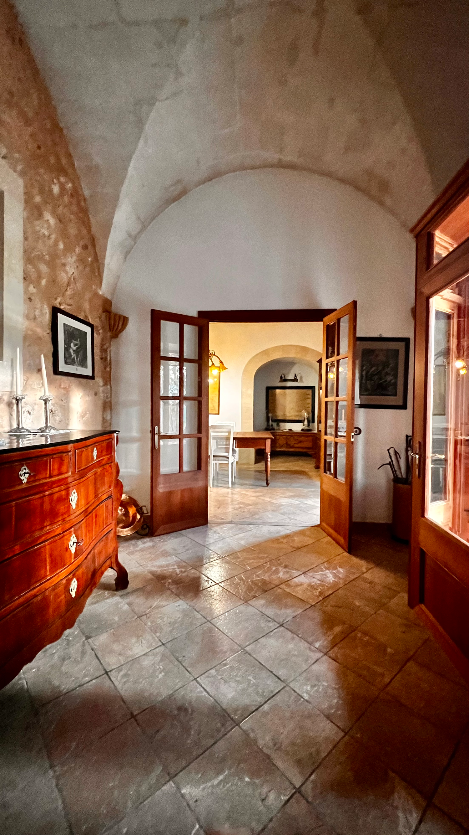 Stone corridor with arched ceiling, wooden furniture, and tiled floor in a historic building shows multiple viewing angles.