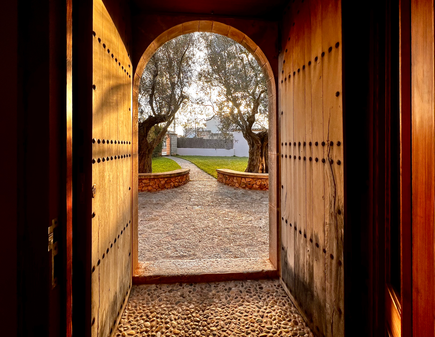 Autumn leaves scattered along a stone path viewed through an arched tunnel passage at dusk.