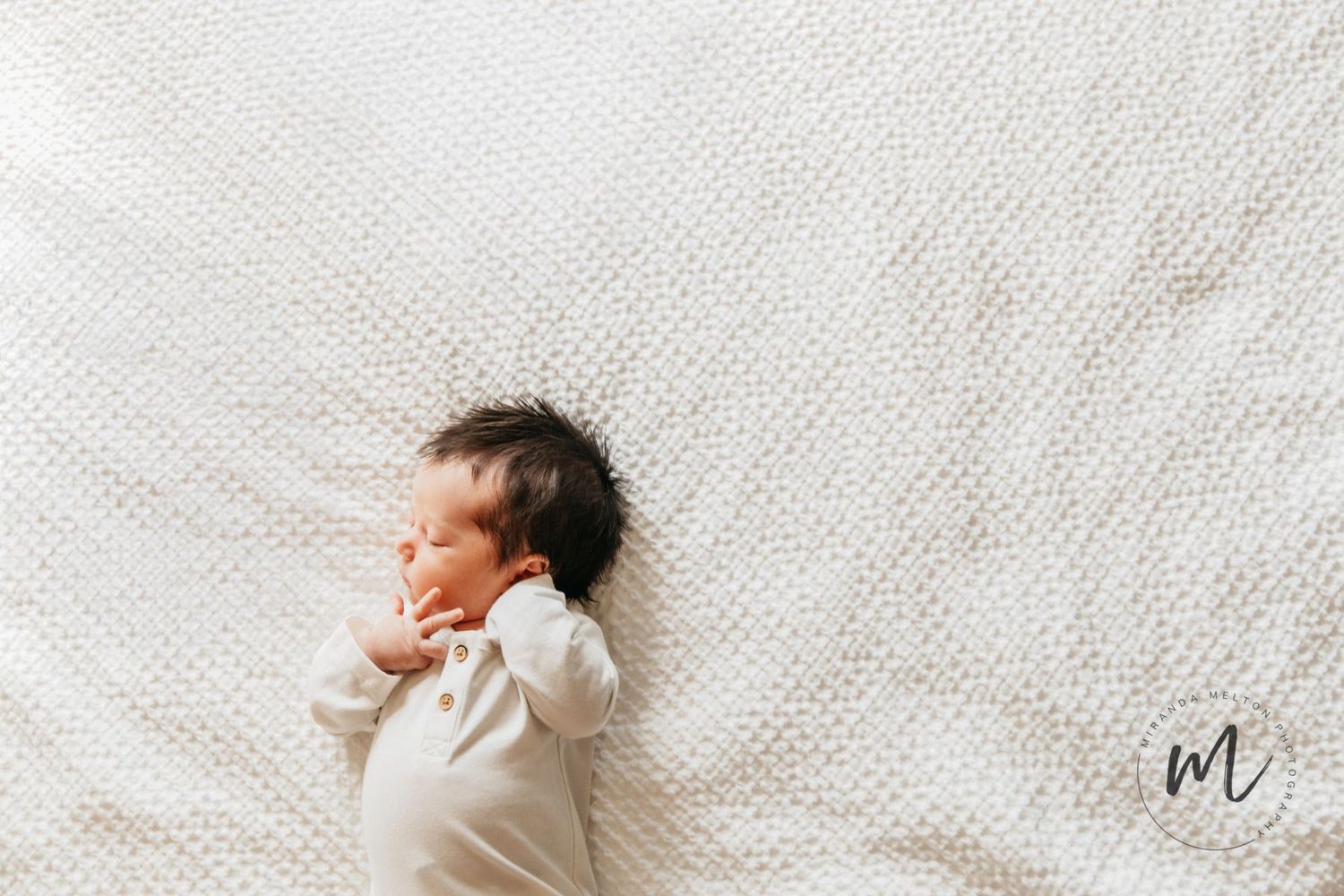 A newborn baby boy is seen on a white blanket at in-home lifestyle newborn photos in New Prague, MN
