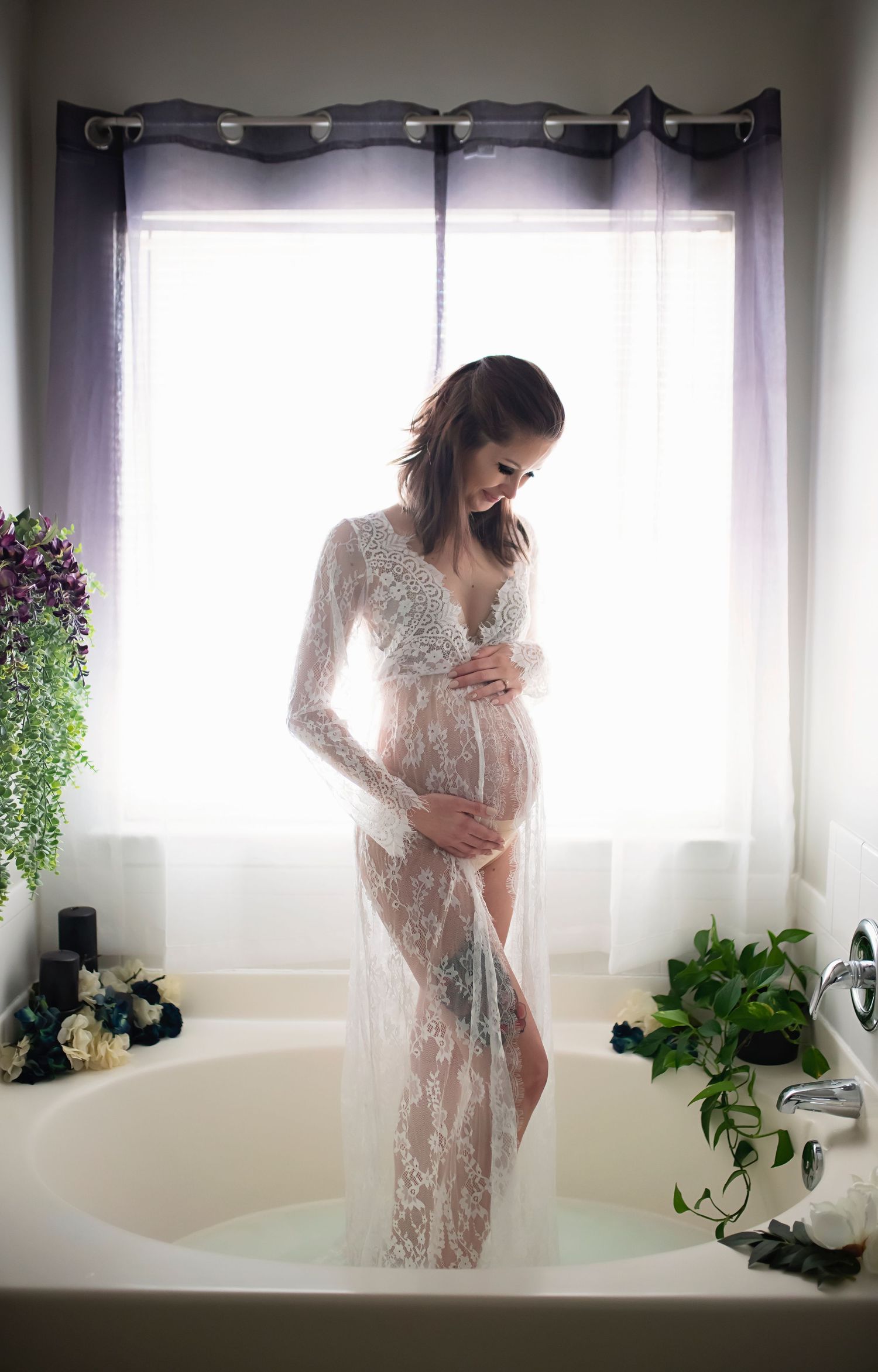 Ethereal maternity photos with white lace dress and window lighting.