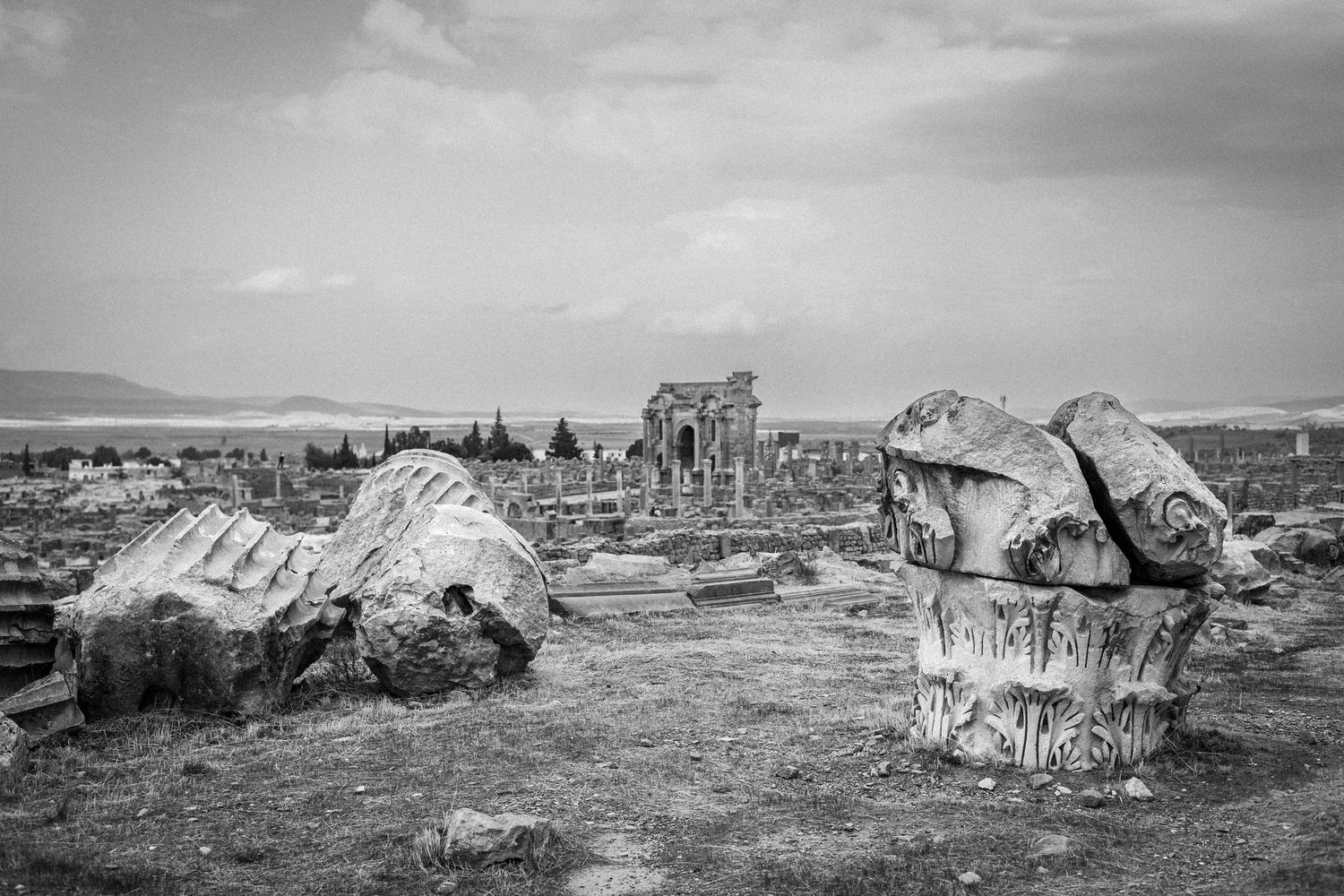 Black and white photograph of deteriorating buildings and ruins in a desolate landscape.