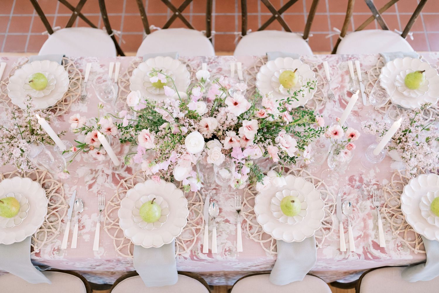 Elegant pink and white table setting with ornate plates and delicate floral centerpieces at a formal event.