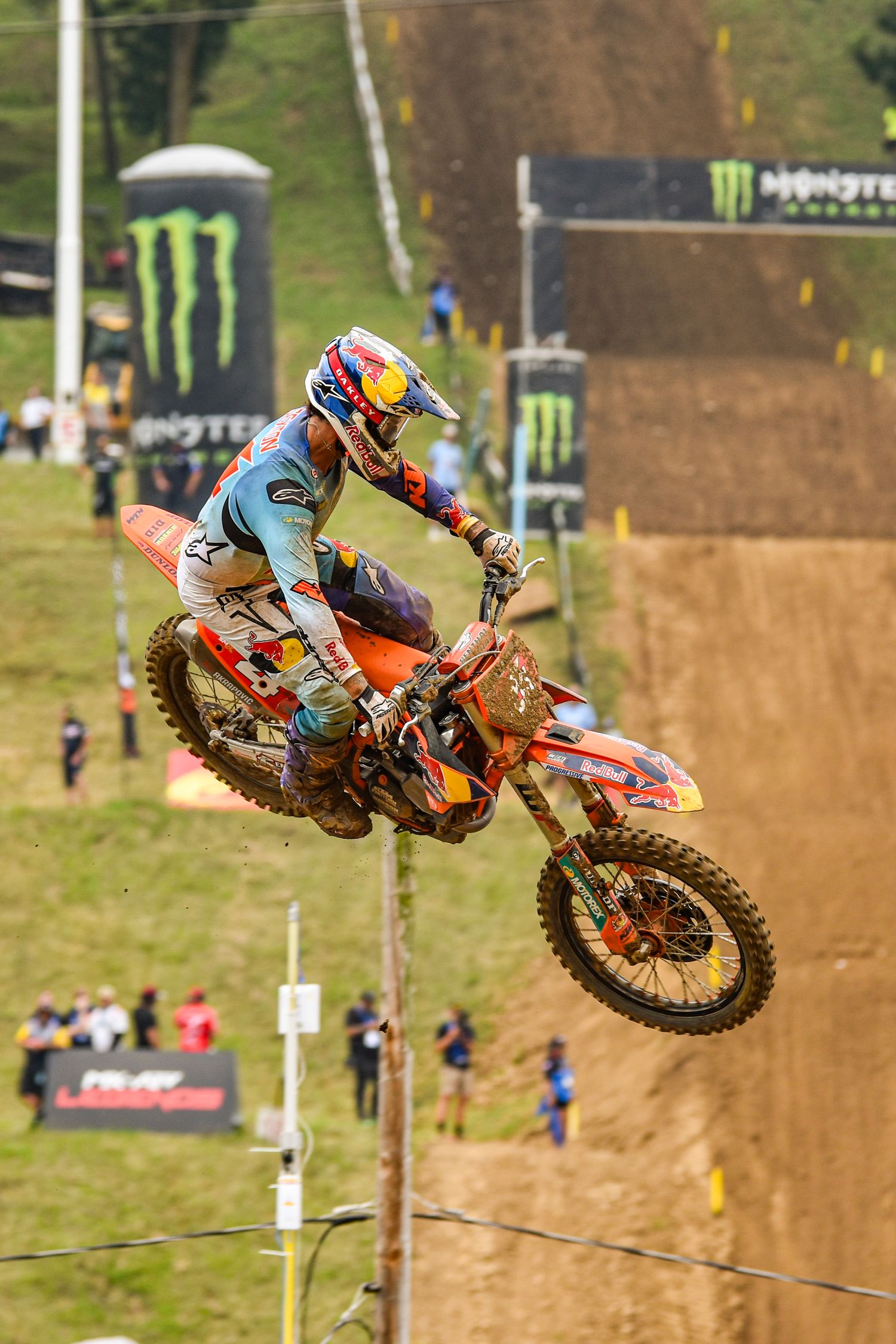 Motocross rider performs dramatic aerial jump on dirt track during competition.