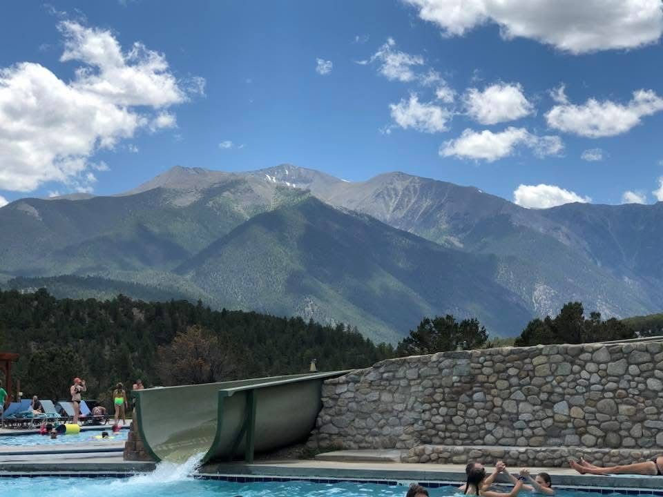 Mountain swimming pool with stunning views of snow-capped peaks and blue skies in the background.