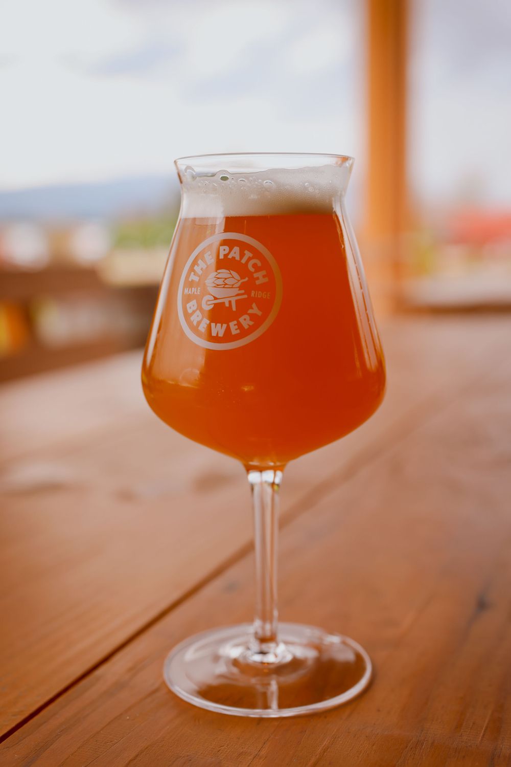 Close-up of hazy IPA beer in tulip glass with brewery logo.