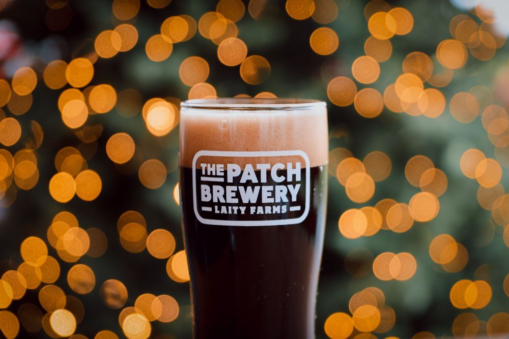 Dark beer from The Patch Brewery against bokeh lights background.