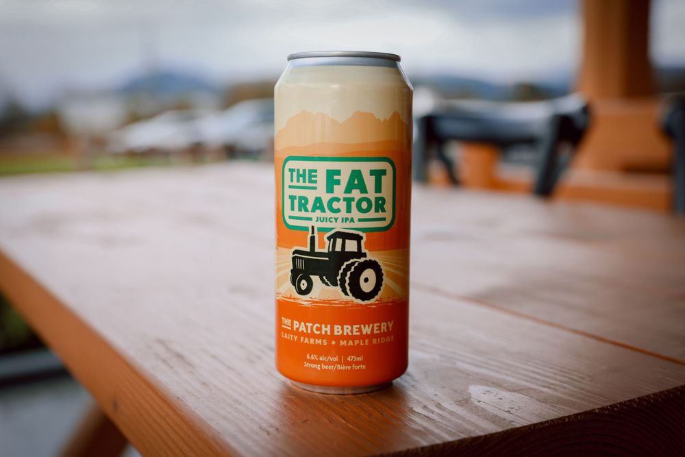 Orange can of 'The Fat Tractor' craft beer sitting on a wooden surface.