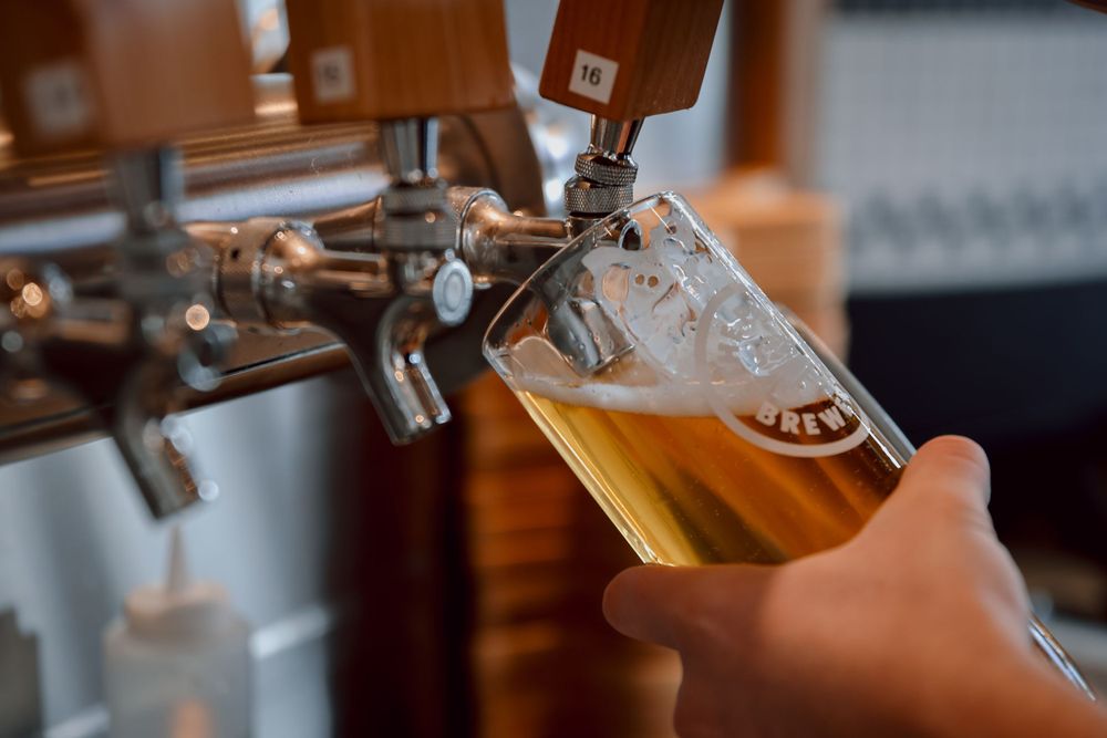 Beer being poured from a tap into a glass with foam forming on top.