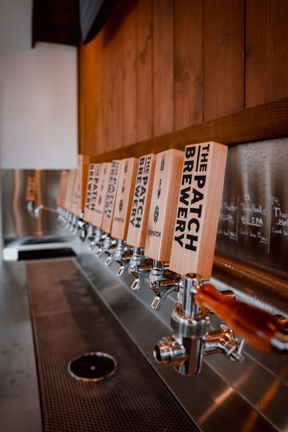 Row of wooden beer tap handles mounted on stainless steel draft system.