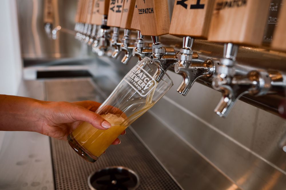 Hand pouring golden craft beer from tap into glass at brewery bar.